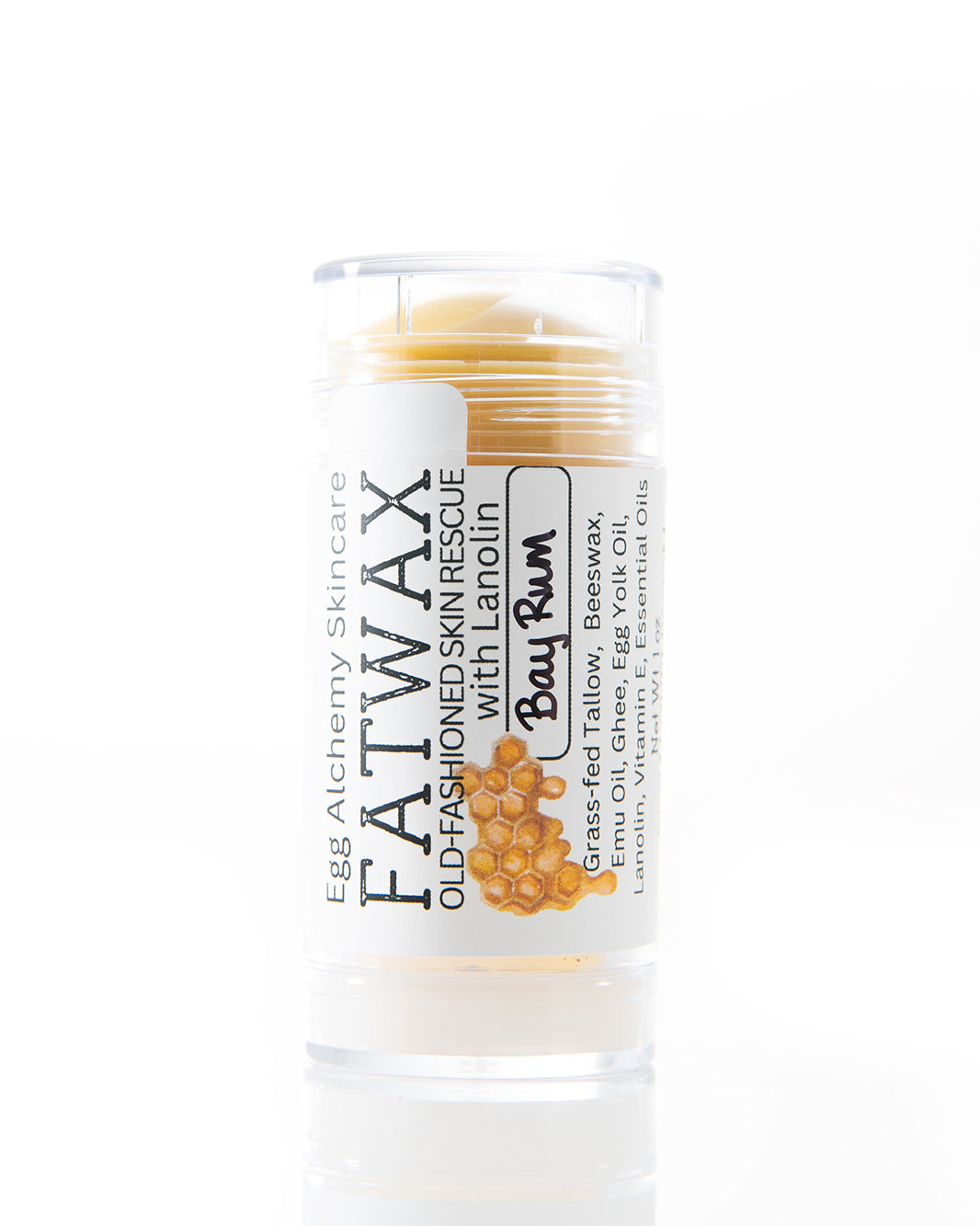 A BPA-free, clear plastic tube is filled with a golden yellow stick balm with a label that reads Egg Alchemy Skincare Fatwax Old-Fashioned Skin Rescue with Lanolin made with grass fed tallow and ghee