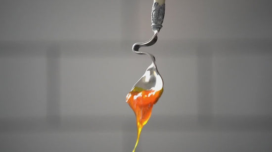 Thick, golden Egg Yolk Oil drips off of a spoon.